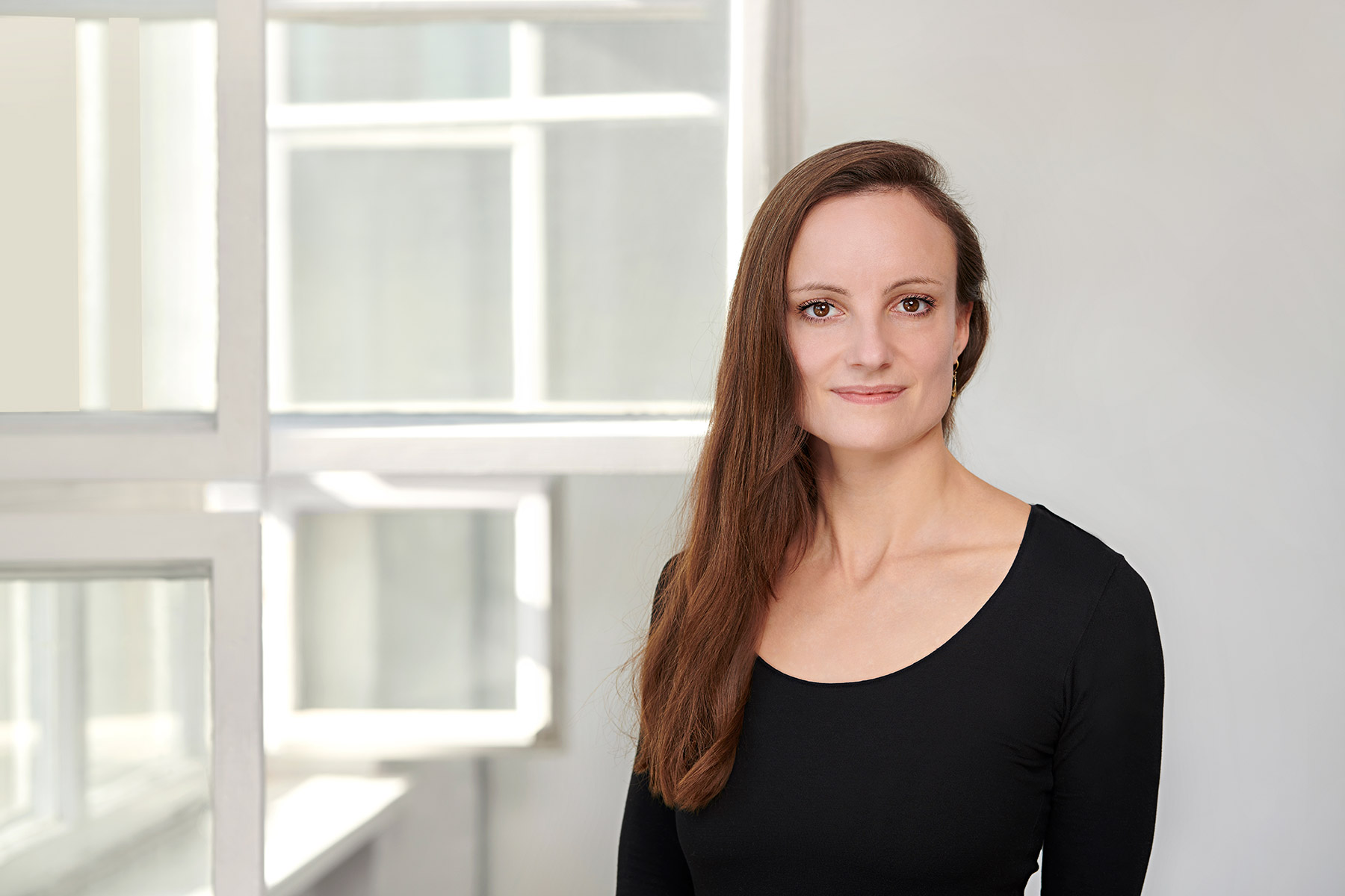 Hey – das bin ich, Anna Stachow von ZOYA | COACHING! Portraitbild von Anna Stachow vor weißem Hintergrund und seitlich geöffneten Altbaufenstern
