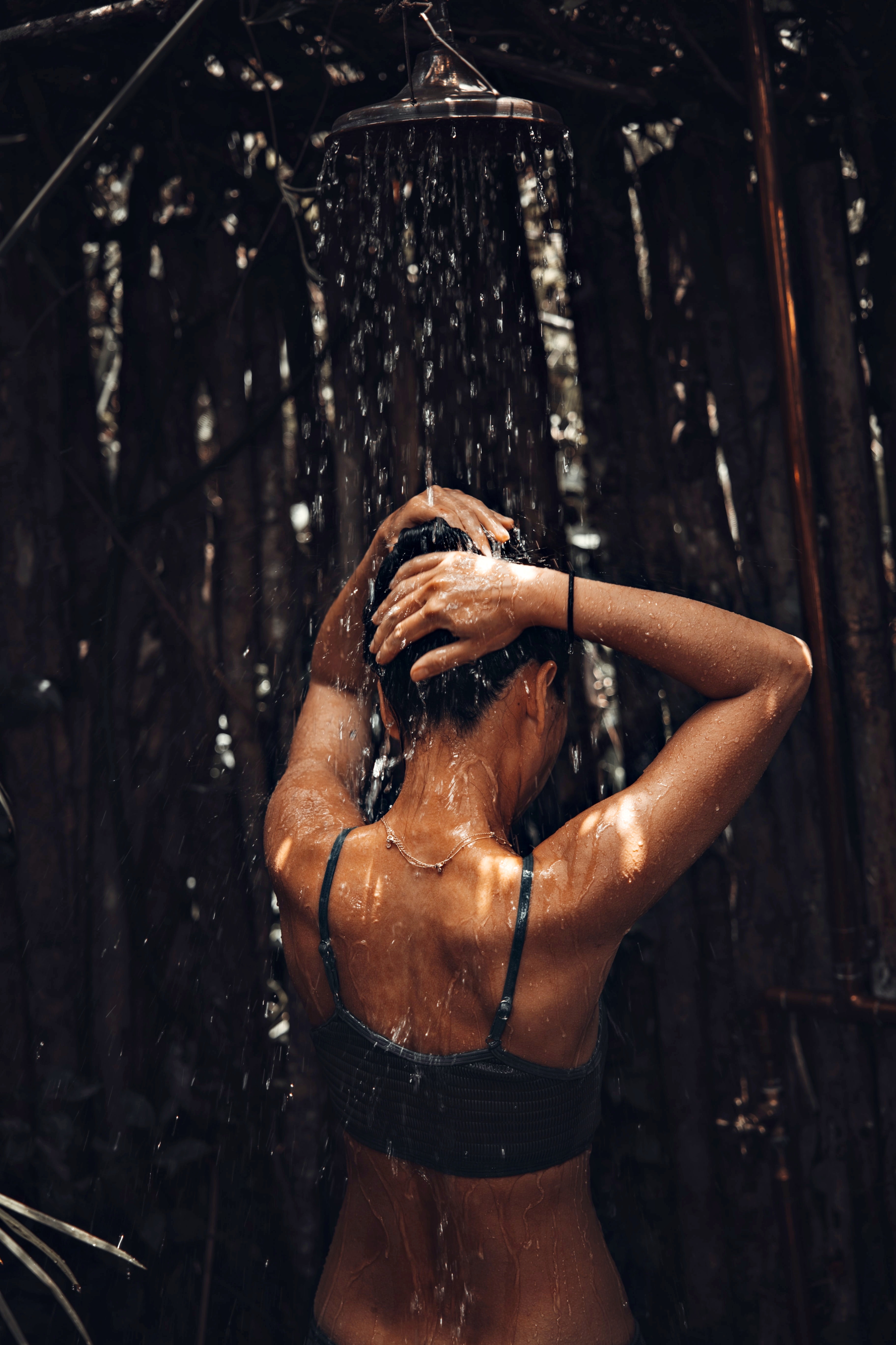 Körperwahrnehmung – Frau unter der Dusche mit dem Rücken zur Kamera